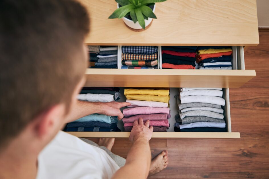 Man organizing color-coded clothing in a neatly folded drawer during spring decluttering